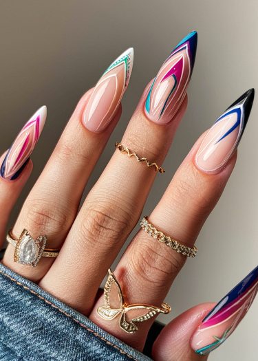 Elegant geometric nail art with rings on a manicured hand and denim fabric backdrop.