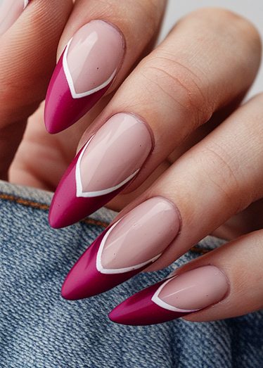 Elegant almond-shaped nails with vibrant magenta tips and chic white V-lines on smooth skin.