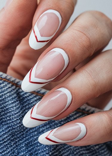 Elegant almond-shaped nails with white and red designs against a denim background.