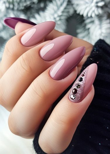 Elegant almond nail design featuring mauve color, glitter accents, and rhinestones for a glamorous look.