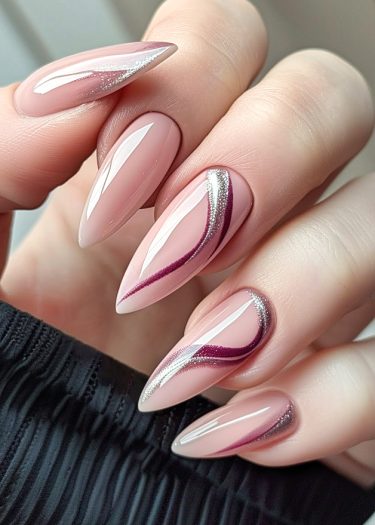 Elegant stiletto nails with glossy pink polish and artistic silver-burgundy designs on a dark background.