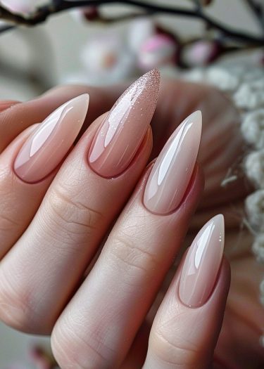 Elegant almond nails with a pink gradient and glittery accent, showcasing sophisticated nail art.