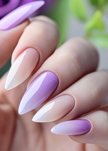 Elegant stiletto nails in creamy nude to lavender ombre, showcasing refined manicure artistry.