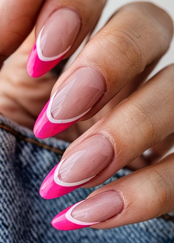 Elegant almond-shaped nails with bold pink tips and chic geometric design on a casual backdrop.