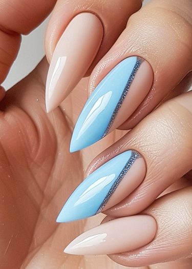 Elegant almond-shaped nails with glossy pastel blue and nude polish featuring stunning nail art.