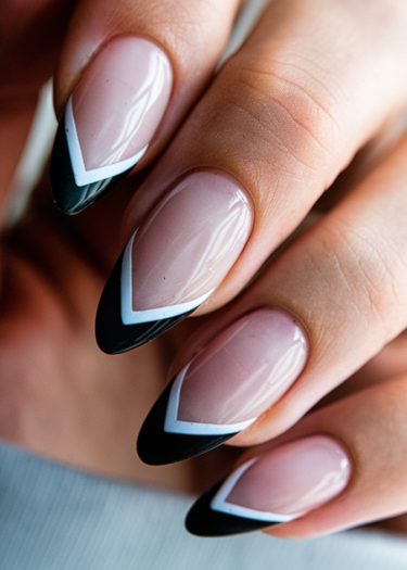 Elegant almond nails with bold black V-tips and crisp white accents for a chic look.