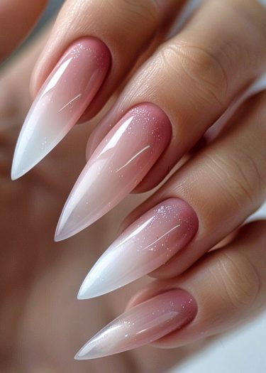 Elegant stiletto nails with blush and white ombre gradient and shimmering finish.