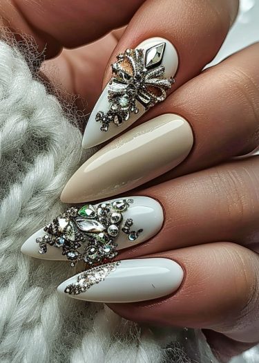 Stiletto nail art featuring elegant beige and white designs with rhinestones and metallic beads.