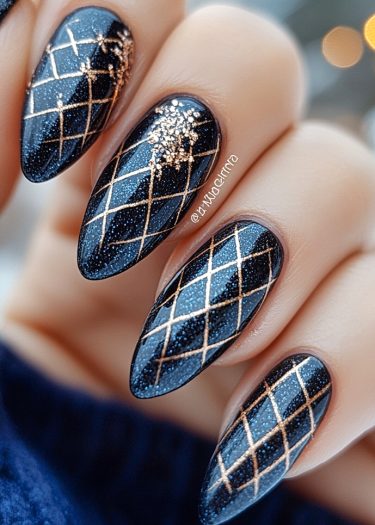 Elegant navy blue almond nails with gold lattice design and glittering accents for a luxurious look.