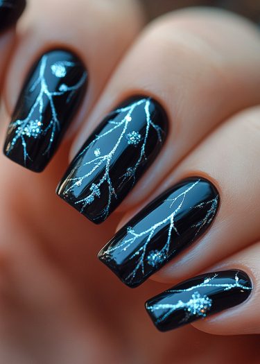 Elegant black nail art featuring intricate silver designs and glossy finish for a sophisticated look.