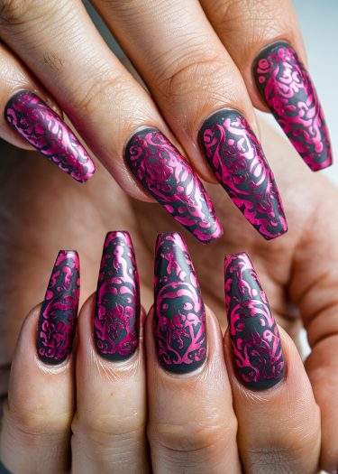 Elegant black nail art with intricate pink floral designs in stiletto shape.