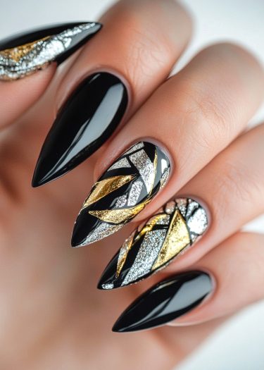 Elegant black nail art with intricate gold and silver geometric designs on almond-shaped nails.