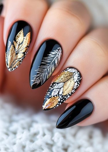 Elegant black stiletto nails feature intricate metallic leaf and feather designs for luxurious nail art.