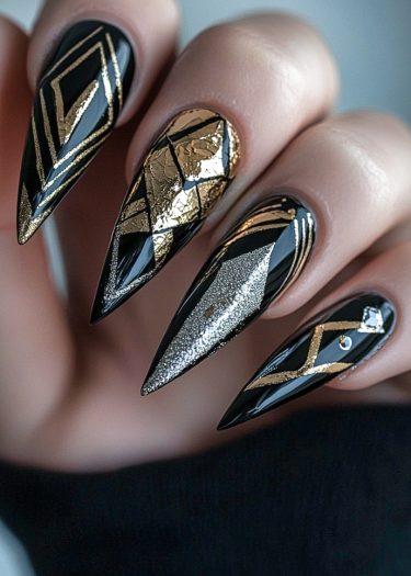 Striking black and gold stiletto nails with geometric designs, foil accents, and rhinestones.