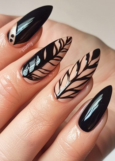 Elegant black and nude nail art with intricate leaf designs and sparkling accents.