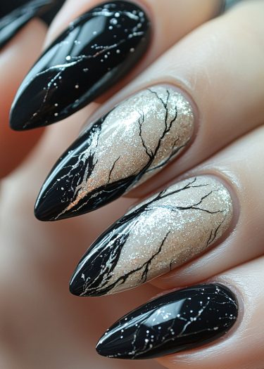 Artistic black and silver nail art featuring glossy patterns and shimmering designs on almond-shaped nails.