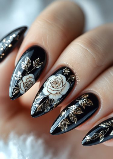 Elegant black almond nails featuring intricate rose designs and gold accents for a luxurious touch.