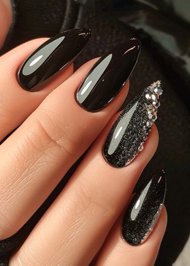 Elegant black almond stiletto nails with rhinestones and glitter effects for a sophisticated manicure.