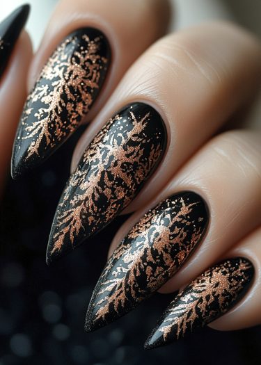 Elegant black stiletto nails with shimmering rose gold coral patterns, showcasing luxurious nail art.