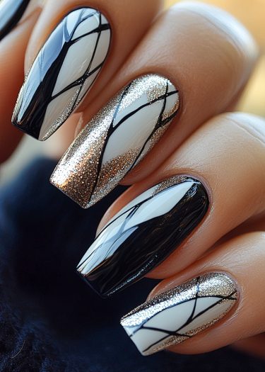 Elegant black and white nail art with shimmering silver glitter and geometric patterns.