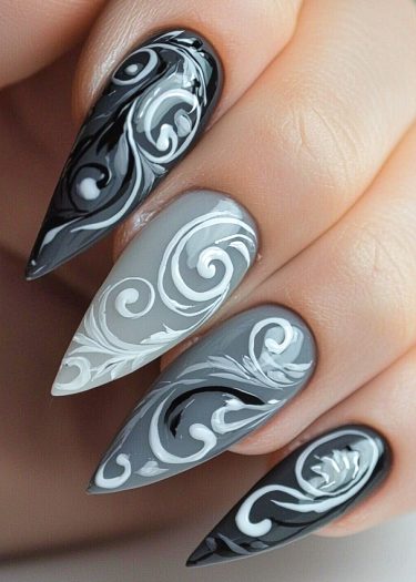 Elegant stiletto nails feature intricate black, white, and grey designs with swirling patterns.