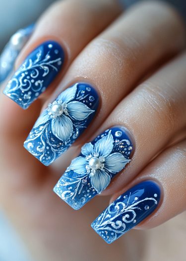 Elegant blue floral nail art featuring intricate designs and pearl embellishments for a sophisticated look.