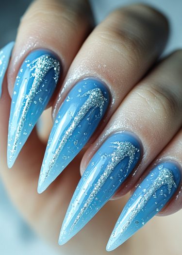 Stunning blue ombré stiletto nails with silver glitter for a glamorous winter look.