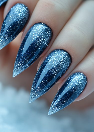 Elegant blue stiletto nails with silver glitter tips, showcasing trendy nail art design.