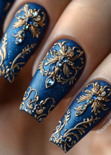 Elegant blue and gold nail art featuring intricate baroque designs and sparkling gemstones.