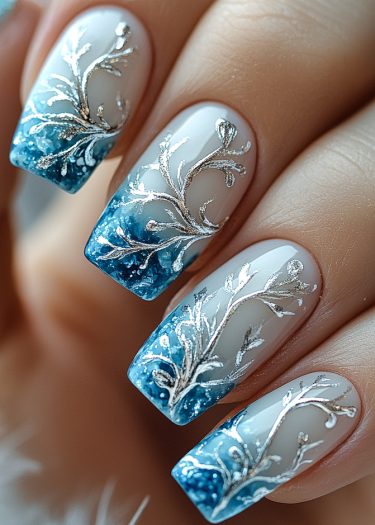 Elegant blue gradient nail art with intricate silver designs for a sophisticated look.