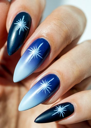 Elegant blue gradient nails with starburst designs, perfect for a celestial-inspired manicure.