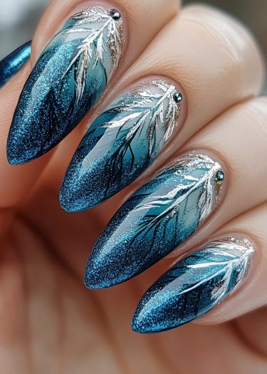 Elegant blue gradient nails with metallic leaf patterns and shimmering accents for a glamorous look.