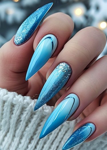 Stunning stiletto nails with a blue ombré gradient and glittery accents for winter elegance.