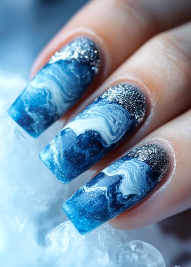 Stunning blue gradient nail art with silver glitter, inspired by ocean waves and elegance.