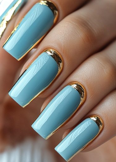 Elegant sky-blue nail art with luxurious gold detailing for a modern, sophisticated look.