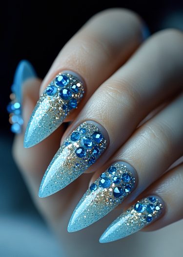 Stunning icy blue stiletto nails adorned with rhinestones and glitter for a luxurious look.