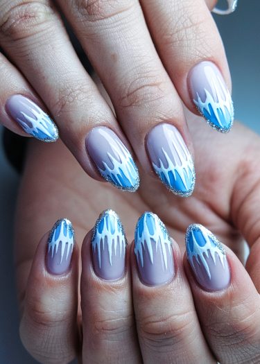 Elegant blue and white almond nail art with gradient and glittering details.