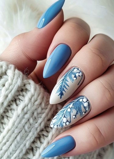 Elegant winter-themed blue and white nail art with intricate designs and almond shapes.