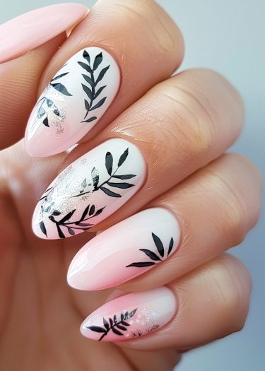 Elegant botanical nail art with gradient polish, black leaf designs, and shimmering glitter accents.