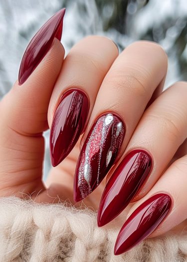 Elegant burgundy stiletto nails with glitter design, beautifully showcased against a cozy cream background.