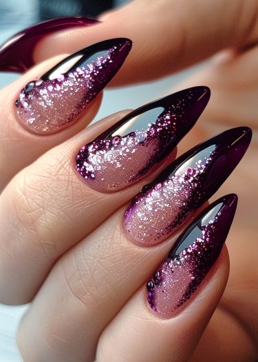 Elegant burgundy ombre nails with stiletto shape and sparkling glitter for a glamorous look.