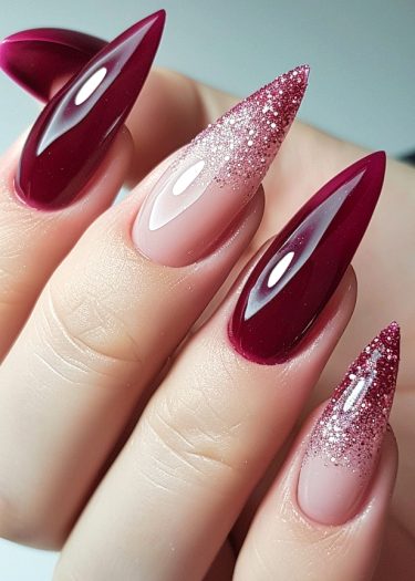 Elegant burgundy stiletto nails with glamorous glitter pink ombre for a stunning manicure.