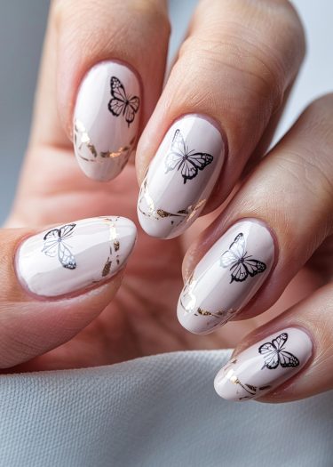 Elegant butterfly nail art featuring pale pink design with gold foil accents and almond shape.