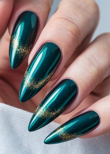 Stiletto-shaped teal nails with gold glitter, showcasing elegant and stylish nail art design.