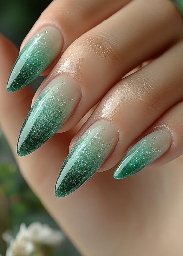 Chic emerald gradient nails with glitter, showcasing elegant almond shapes and smooth skin.