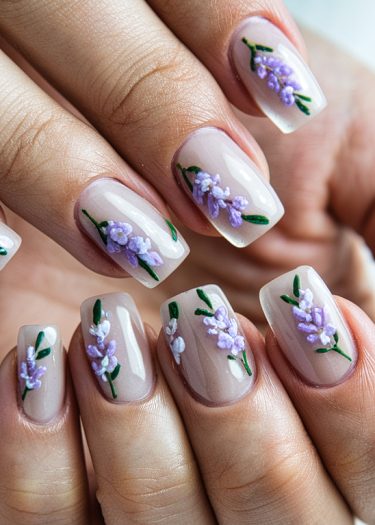 Elegant floral nail art featuring lavender designs on a glossy nude base.