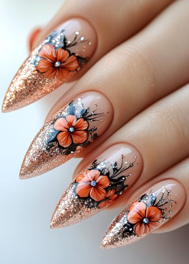 Elegant floral nail art featuring orange flowers, gold glitter, and intricate detailing on long nails.