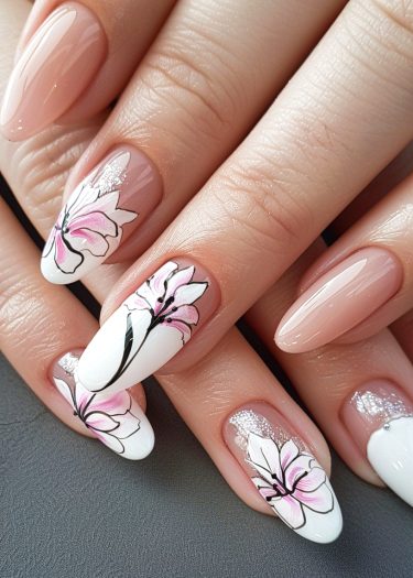 Elegant floral nail art featuring pink flowers and glitter on a nude almond-shaped manicure.