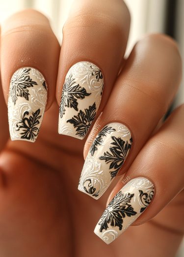 Elegant floral nail art features intricate black designs on creamy white nails for sophisticated style.