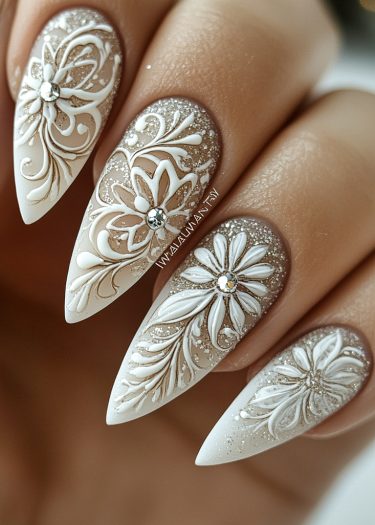 Elegant stiletto nails with floral designs, glitter, and rhinestones for luxurious nail art.